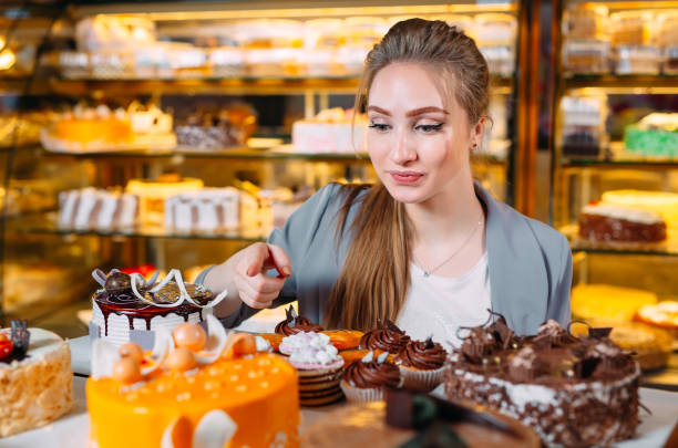 girl looking at the bakery window with different pieces of cakes. - cake pick imagens e fotografias de stock