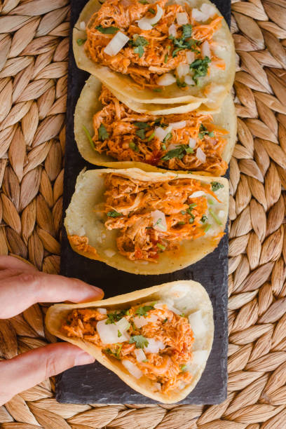istock Mexican tacos on a row and a hand holding one 1268275490