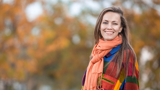 Autumn woman  wearing warm woolen clothes in bright colors walking in autumn park