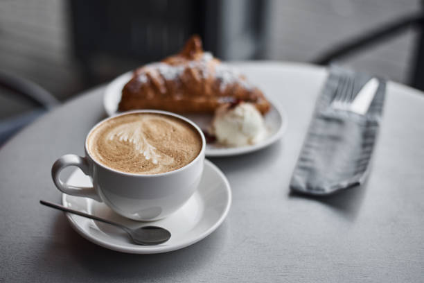 istock Cup of coffee and croissant on table in cafe 1268284835