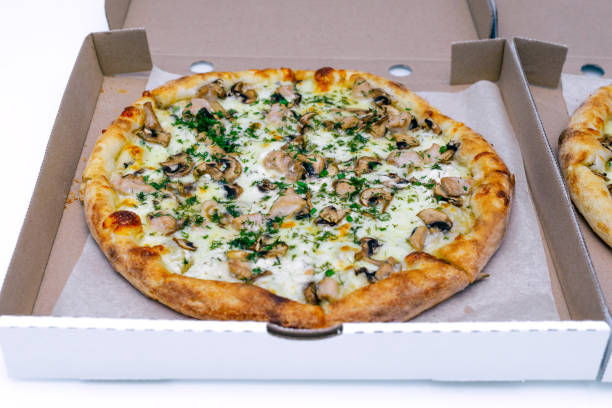 istock Two pizzas in a cardboard box on a light background. Top view. Pizza delivery. Pizza menu. Pizza on the kitchen table. 1268288114