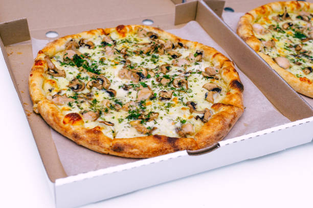 istock Two pizzas in a cardboard box on a light background. Top view. Pizza delivery. Pizza menu. Pizza on the kitchen table. 1268288117