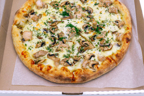 istock Pizza in a cardboard box on a light background. Top view. Pizza delivery. Pizza menu. Pizza on the kitchen table. 1268288134