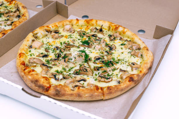 istock Two pizzas in a cardboard box on a light background. Top view. Pizza delivery. Pizza menu. Pizza on the kitchen table. 1268288136