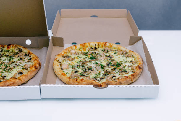 Two pizzas in a cardboard box on a light background. Top view. Pizza delivery. Pizza menu. Pizza on the kitchen table.