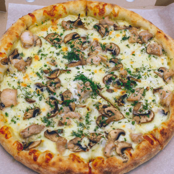 istock Pizza in a cardboard box on a light background. Top view. Pizza delivery. Pizza menu. Pizza on the kitchen table. 1268288151