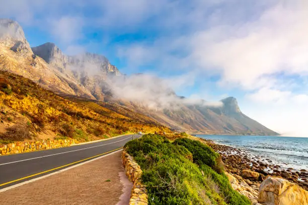 This image shows amazing Garden Route with mountains and clouds and highway road near Cape Town, South Africa