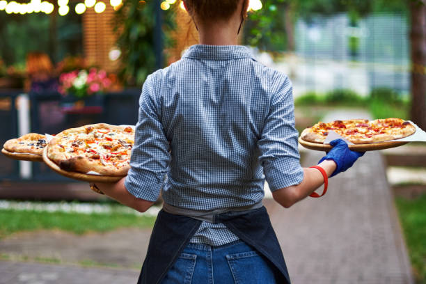 serveur de fille avec son dos à nous avec trois oiseaux dans ses mains sur la terrasse de restaurant - pizza pizzeria restaurant waiter photos et images de collection