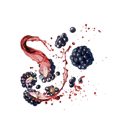 Whole and sliced blackberries with splashes of juice on a white background