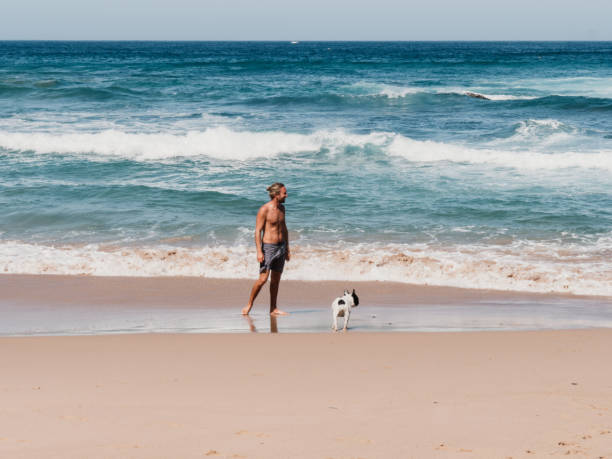 istock Young man playing with dog on beach 1268295015