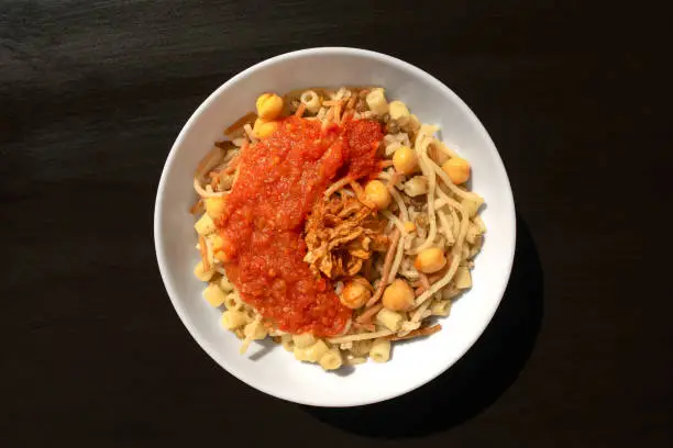 Photo of Egyptian dish - Koshari. National Kushari in a white plate on dark wooden background