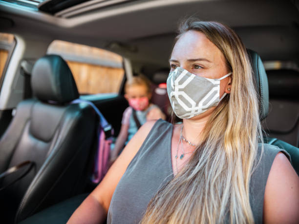 istock Mother and Daughter with masks inside the car 1268297499