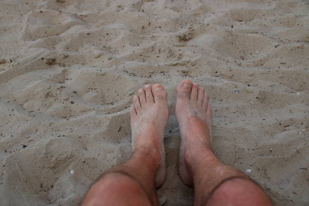 istock Feet on a sandy beach are covered with sand 1268297652