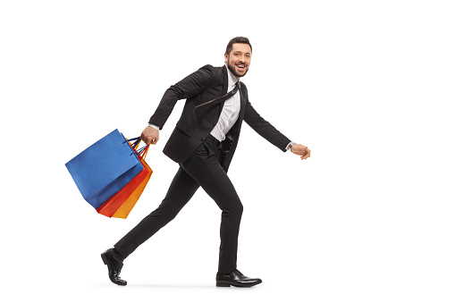 Man in a suit running with shopping bags isolated on white background