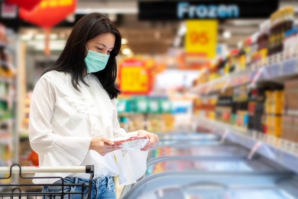 joven asiática hermosa mujer sosteniendo comida congelada en el supermercado. ella mira los productos. concepto de compra. - supermarket meat women packaging fotografías e imágenes de stock