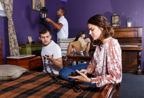 Friends looking at wooden rosary in quest room Young friends looking at wooden rosary while solving conundrum as detectives in quest room with old furnitures riddle stock pictures, royalty-free photos & images