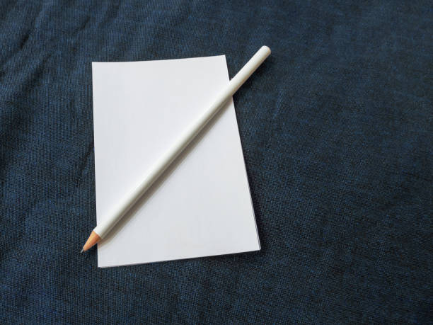 белый лист бумаги с белым графитовым карандашом лежит на синей поверхности ткани - graphite lavender coloured colors education стоковые фото и изображения