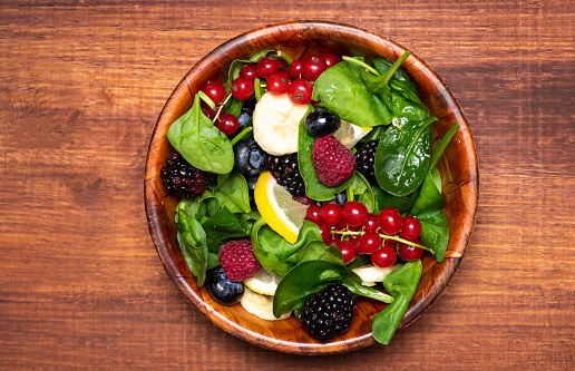 Mixed berry fruit salad with basil leaves on a plate top view