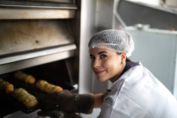 istock Female baker taking fresh bread out of the oven 1268305835