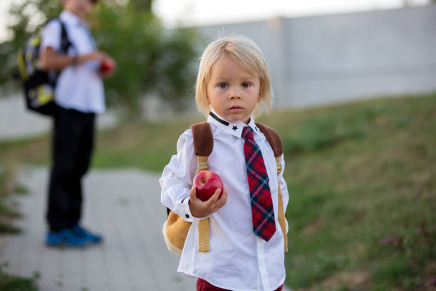 istock Cute preschool child, holding apple, dressed in uniform, going to preschool for the first time 1268307320