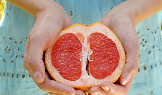 Grapefruit half in female hands