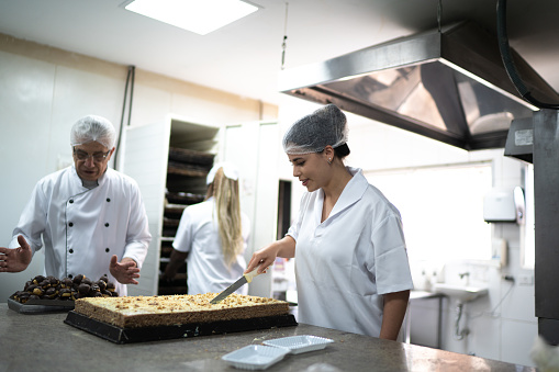 Two chefs arranging desserts in a commercial kitchen