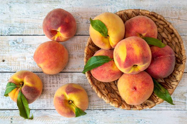 istock Ripe peaches on a white rough wooden table. Top view. 1268316434