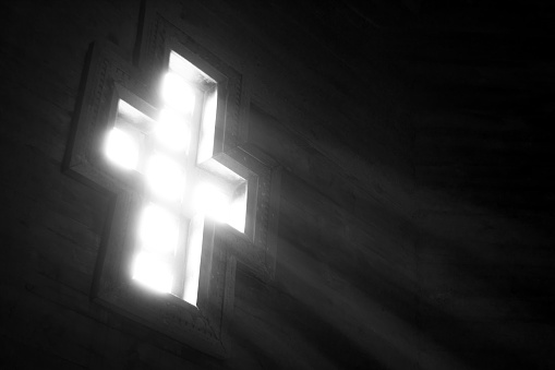 Light falling through the cross-shaped window in an old wooden church.