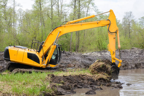 Excavator picks up big amount of soil for construction irrigation system canal in countryside for watering Excavator picks up big amount of soil for construction irrigation system canal in countryside for watering river system stock pictures, royalty-free photos & images