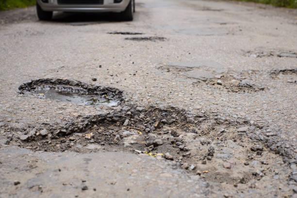 istock Many enormous potholes in asphalt surface. Concept of bad road, problems with road pavement 1268318062