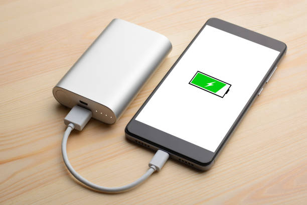 istock Modern smartphone lays on light wooden table while charging with power bank with quick charge 1268318079