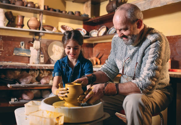 istock Pottery workshop. Grandpa teaches granddaughter pottery. Clay modeling 1268318429