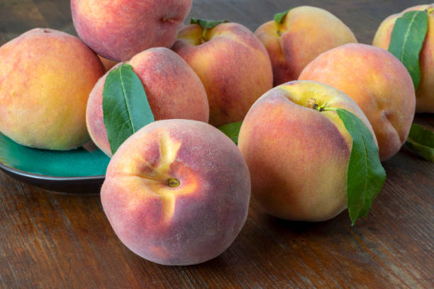 istock Peaches on a plate on a brown wooden table. 1268319714