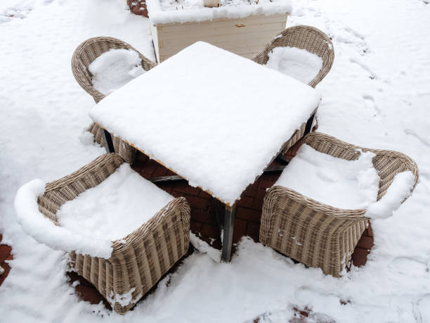 istock A square table with four wicker rattan chairs strewn with snow stands on a snow-covered tile 1268321882