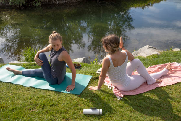 junge frauen führen yoga-moves auf der bachwiese durch - nature zen like stream water stock-fotos und bilder