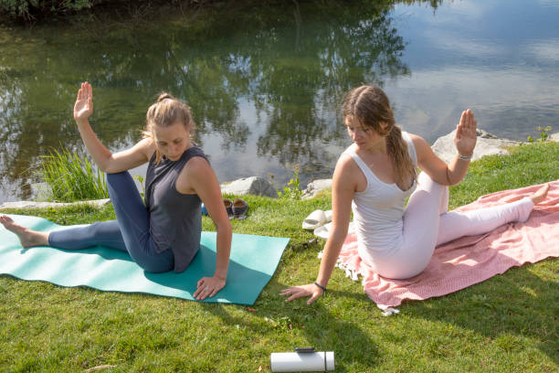 junge frauen führen yoga-moves auf der bachwiese durch - nature zen like stream water stock-fotos und bilder