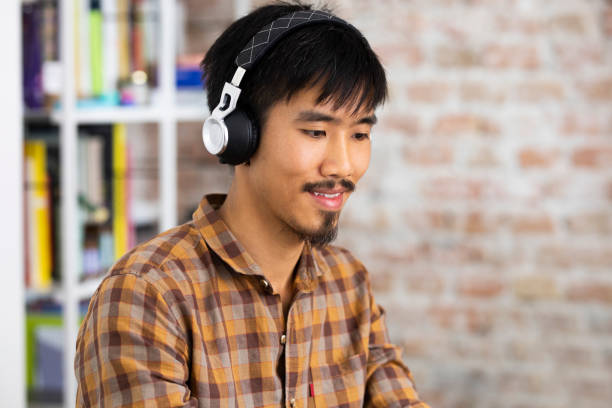 istock Smiling Asian College Student Wearing Wireless Headphones While Attending an Online Course in the University Library 1268334185
