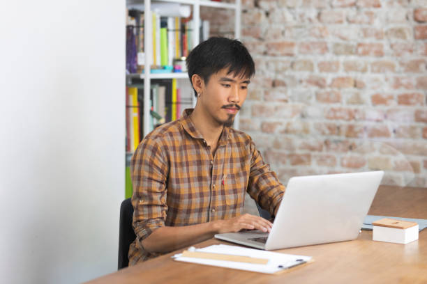 istock Asian Businessman Working on his Laptop Computer at a Modern Company 1268334192