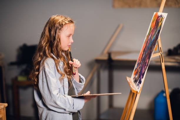 istock Young girl creative artist at work in a workshop. With passion draws a picture immersed in work 1268340986