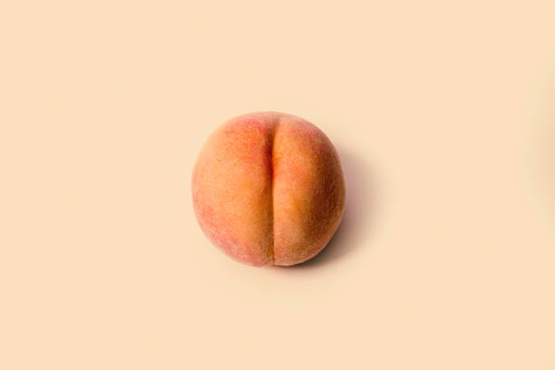 Fresh Peach on Peach Colored Background A detailed image of a freshly picked ripe peach.  Photographed on a peach colored background. peach photos stock pictures, royalty-free photos & images
