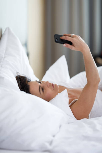 istock Beautiful young woman sleeping using her smart phone in bed first thing in the morning 1268341919
