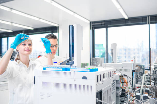 Two young researchers  carrying out scientific research in a lab Two young researchers  carrying out scientific research in a lab using a gas chromatograph (shallow DOF; color toned image) chromatography stock pictures, royalty-free photos & images