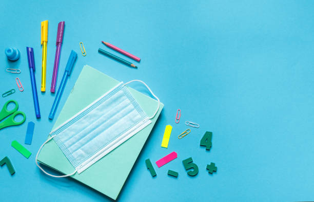istock Items for Returning to school. Bright office supplies, a protective mask and a container for home food. Layout on a blue background 1268349298