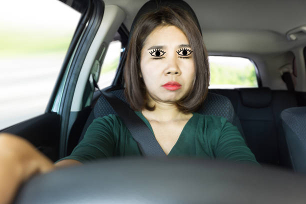 istock Tired Asian woman fall sleeping  while driving the car 1268352346