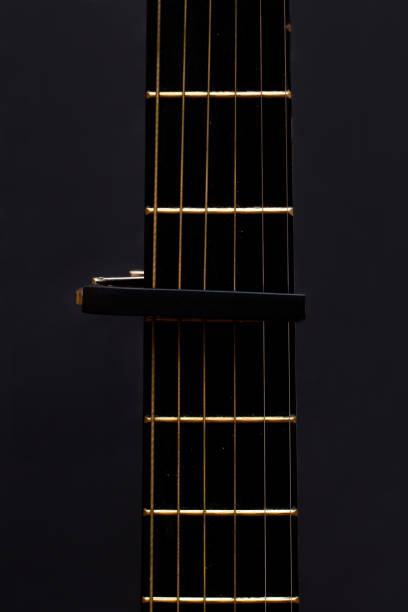istock Cap on guitar fretboard on black background. Close plan. Wooden guitar. 1268355984