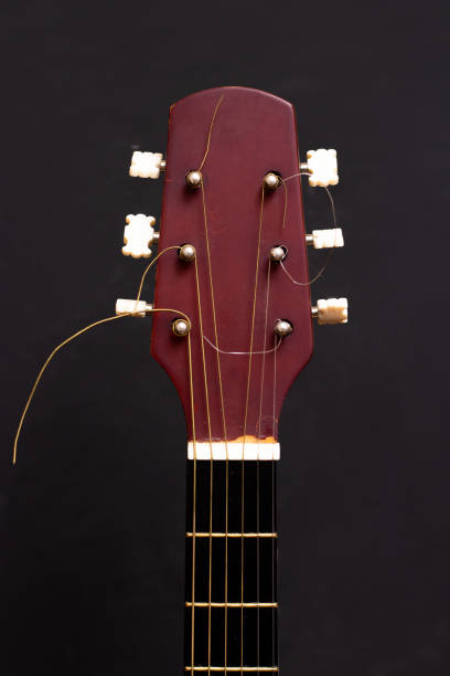 istock Guitar head and neck on a black background. Wooden acoustic six-string guitar. 1268355995