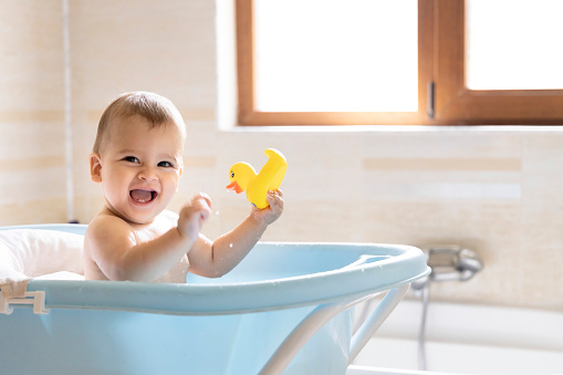 A cute baby is bathing in the tub. A baby who splashes water while bathing