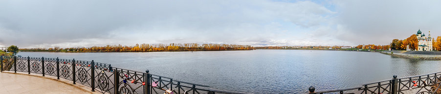 Beautiful lake and yellow trees in an autumn cloudy day. Panoramic landscape.
