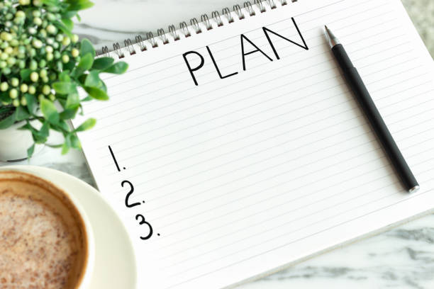 istock Notepad with the inscription plan and cup of coffee on marble background. 1268369643
