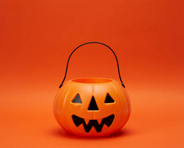 istock Jack o lantern pumpkin on orange background 1268385867